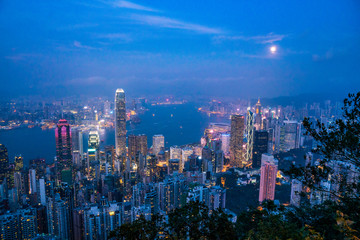 Obraz premium Full moon rise over Hong Kong Skyline at dusk. Modern China city with skyscrapers near the ocean