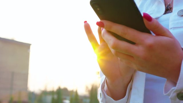 Woman texting on smartphone looking happy outside, Caucasian girl in her 20s happily texting on phone in public place, 4k