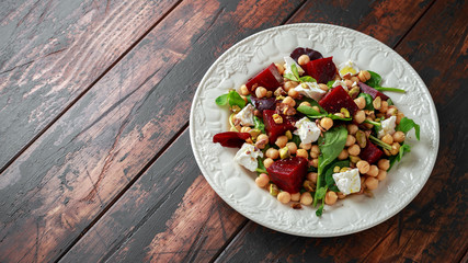 Healthy Beet Salad with chickpeas, pistachios nuts, feta cheese on rustic wooden background