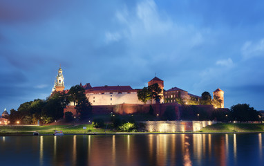 Obraz premium Wawel Castle at night with the river Vistula at the foreground. Ancient castle lights reflection in the water. High resolution panorama.