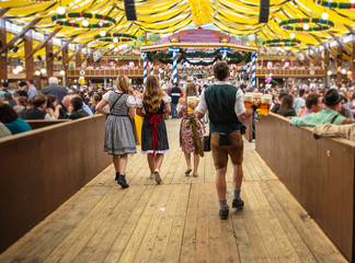 Fototapeta premium Oktoberfest, Monachium, Niemcy. Kelner trzymając piwa, tło wnętrze namiotu