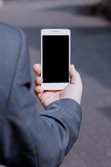 A man in a suit holds a white smartphone