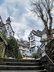 Monschau street view with preserved old half-timbered buildings against a moody overcast March sky,...