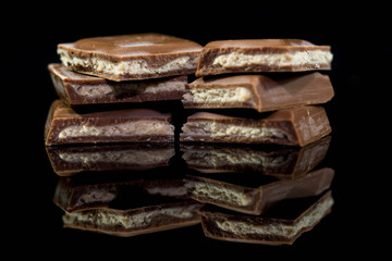 Delicious brown chocolate pieces filled with caramel cream close up macro shot on dark reflecting background.
