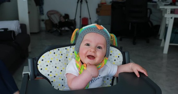 Beautiful Baby Boy With A Funny Colored Wool Hat On The Head, Cute Six Month Old Baby Boy In High Chair. Close Up View - DCi 4K Resolution
