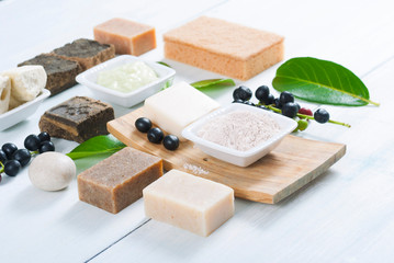 cosmetic clay, soaps, henna blocks, sponge and moisturizer on white wood table