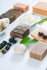 cosmetic clay, soaps, henna blocks, sponge and moisturizer on white wood table