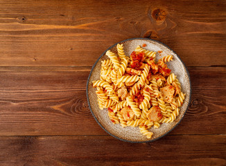 fusilli pasta with tomato sauce, chicken fillet on dark brown wooden background, copy space, top view