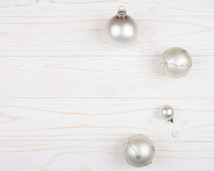 Christmas balls of a silver color on a white wooden background (copy space on the left for your text, top view) as a New Year or Christmas background
