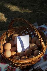 Wicker basket with eggs for sale and a white blank paper.