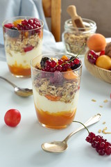Dessert with cream, jam, muesli and fresh berries in a glass, vertical 
