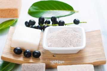 cosmetic clay, soaps, henna blocks, sponge and moisturizer on white wood table