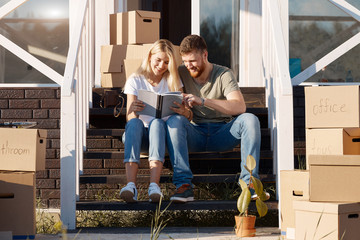 Husband and wife standing in front of new buying home with boxes. bought first home
