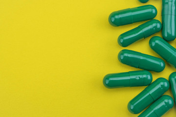 Some capsules greens isolated on a yellow background, conceptual image