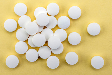 Some tablets white isolated on a yellow background, conceptual image