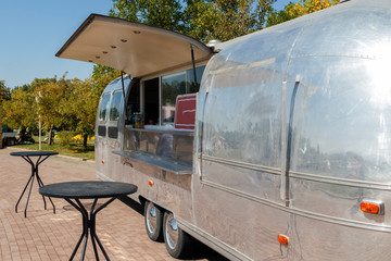 Metal trailer for selling food and tables for visitors stand on the street waiting for buyers. Copy space