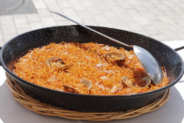 traditional spanish fideua in black frying pan, open air food 