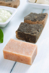 cosmetic clay, soaps, henna blocks, sponge and moisturizer on white wood table