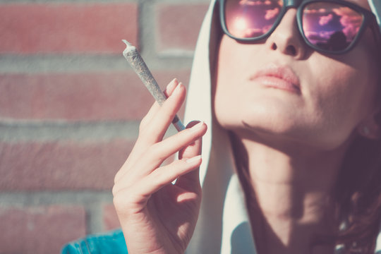 Young woman with weed joint. Marijuana and cannabis legalisation concept.