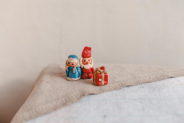 New Year, Santa Claus (Father Frost) and Snow Maiden, Christmas card. Plasticine figurines on a textile linen surface. Foreground out of focus gift