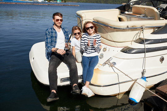 Young Family With Daughter Fishing On Yacht Sailboat On Lake