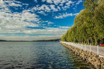 vivid waterfront walking space with trees square and colorful blue sky and clouds