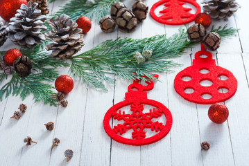 Christmas decoration background: red balls and felt ornaments pine and cypress cones with twigs on white wood table