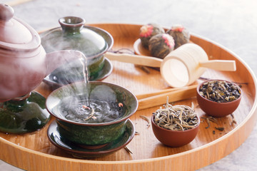 Boiling water from a ceramic kettle is poured into a traditional Chinese porcelain cup at a tea ceremony