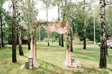 The square arch decorated by fabric of pink color and fresh with flowers