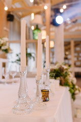 Thin glass candlesticks with ong white candles.