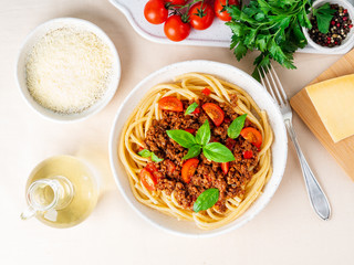 pasta bolognese with tomato sauce, ground minced beef, basil leaves on white table, linen napkin, top view