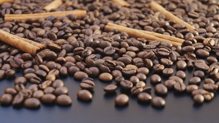 Placer coffee beans and cinnamon sticks on a dark background 