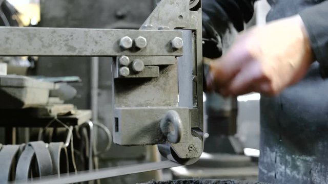 Grinding billets of metal knife on a belt-grinding machine. Close-up of a man's hands.