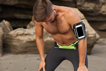 Active sportsman catches breath after covering long distance running outdoor, has activity tracker...