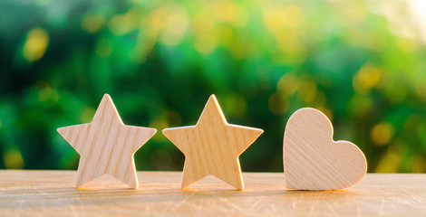 two stars and heart on a green bokeh background. three star rating, the choice of the editorial office and the buyer. concept of rating, review. quality, service. selective focus