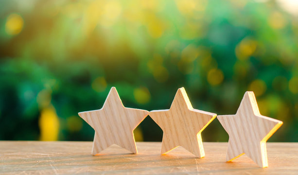 three wooden stars on a background of green bokeh background. The concept of the rating of hotels and restaurants, the evaluation of critics and visitors. Quality level, good service. selective focus