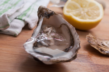 closeup of  oysters and lemon on wooden cutting board