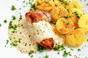 chicken breast under sour cream mustard sauce garnished with potato and sprinkled with parsley