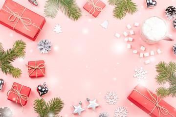 Christmas background with fir branches, lights, red giftboxes, pink decorations, hot drink with marshmallows on pink
