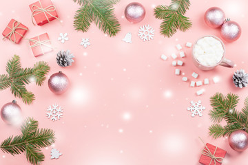 Christmas background with fir branches, lights, red giftboxes, pink decorations, hot drink with snow falling