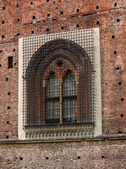 Fototapeta na wymiar Sforza Castle in Milan, northern Italy. Window on the fortress wall. On the window is a steel lattice