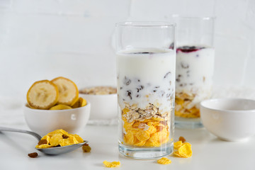Breakfast in glass Cup: homemade granola, banana, fresh berries, yogurt on white background. The concept of healthy eating, high-carbon Breakfast.