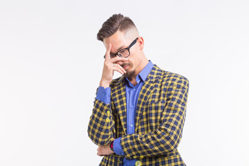 Emotions and people concept - handsome young man in jacket with beard and whisker in glasses thinking about something over white background