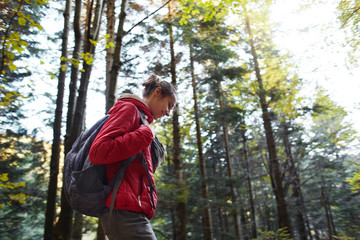 happy smiling woman in a red jacket walks in the autumn forest