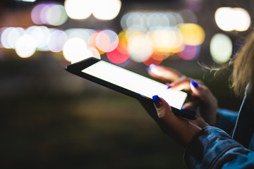 woman hand using digital tablet on night beauty light bokeh in city