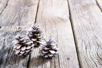 three white painted pine cones Christmas decoration on old rustic wooden table background