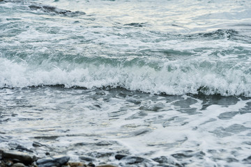 Sea wave surf crashing onto the pebble beach.