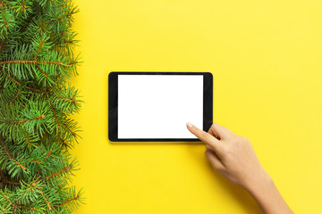 people and technology concept, close up of female hands pointing finger to tablet. blank screen on yellow background, top view