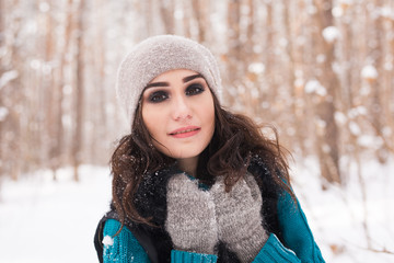 Portrait of young pretty woman walking in the winter snowy park at sunny day