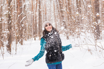 Fototapeta na wymiar Young pretty woman throwing snow in the air in winter holidays